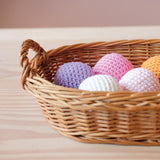 Im flachen Weidenkorb liegen Häkelbälle von Kokomoo in verschiedenen Farben.