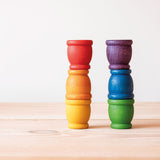 Grapat "Mates" Toepfchen aus Holz in 6 Regenbogen Farben stehen als zwei Saeulen zu je 3 gestapelten Toepfchen nebeneinander.