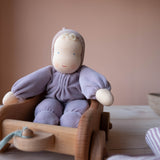 Die Grimms Kuschelpuppe Viola sitzt in einem kleinen Nachziehwagen aus Holz.