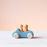 Grimms Holzauto blau mit zwei gelben Spielfiguren aus Holz im Spielauto.