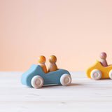 Grimms Holzauto zum Spielen in blau, darin zwei Spielfiguren aus Holz.