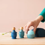 Blaue Grapat Holzzwerge in blauen Töpfchen, daneben wird ein hellblauer Häkelball von Kokomoo von einer Hand in ein blaues Schälchen gelegt.