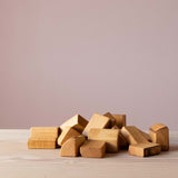 Geölte Holzbauklötze mit Rinde und ganz unterschiedlicher Form - liegen übereinander auf einer Holzplatte