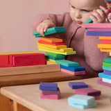 Ein Kind stapelt die Holzbausteine von Glückskäfer mit der flachen Seite zu einem Turm.