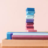 Ein Turm aus dreizehn Glückskäfer Holzbausteinen in den Farben lila, rosa, hellblau und dunkelblau.