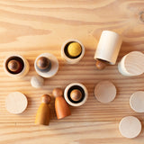 Kleine Holzdosen mit Deckel, teilweise offen und kleine Spielfiguren aus Holz darin oder Filzkugeln.