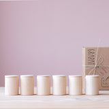 Sechs glatte Holzbecher Cups von Grapat, mit Deckel, stehen in einer Reihe.