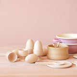 Utensilien für die Puppenküche: Holzeier und Eierbecher aus Holz, Schalen, kleine Kochlöffel und Teller aus Holz, Kochtöpfe aus Emaille.
