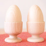Zwei Holzeier im Eierbecher aus Holz von Kokomoo nebeneinander aufgestellt.