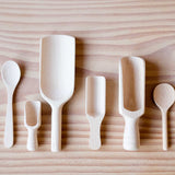 Das 6er-Set Holzlöffeln und Holzschaufeln von Kokomoo: alle sechs verschieden geformten und größere und kleine Holzlöffeln sind nebeneinander aufgelegt.