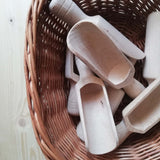 Sieben kleine Holzschaufeln zum Spielen für junge Kinder liegen in einem Korb.