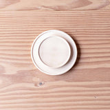 Zwei kleine Holzteller aus Ahornholz, unterschiedliche Größen, liegen übereinander gestapelt, das größere unten.