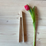 Die Holzzange von Kokomoo liegt neben einer Tulpe zum Größenvergleich.