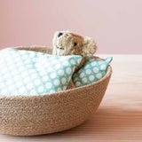 Im Jutekorb von Respiin schläft ein kleiner Kuschelbär, weich gebettet und zugedeckt mit Gewichtssäckchen von Kokomoo.