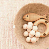 Der Jutekorb von Respiin ist gefüllt mit der Urfisch Babyrassel von Kokomoo, dem Kugelgreifling natur und der Dreilochring Rassel von Kokomoo.