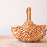 Das Kinderkörbchen von Kokomoo aus Weide, mit Henkel, seitlich zu sehen.