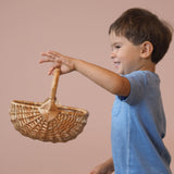 Ein Kinder hält einen kleinen Korb von Kokomoo, geflochten aus Weide hoch.