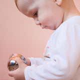 Ein Baby hält zwei Kinder Klangschalen in den Händen, setzt sie ineinander und schaut konzentriert darauf.