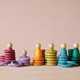 Das Grapat "Nins, Rings & Coins" Holzfiguren-Set in erdigen Komplementärfarben teilweise aufeinander, ineinander und nebeneinander aufgestellt.