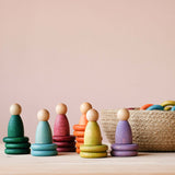 Die 6 Nins des Grapat "Nins, Rings & Coins" Holzfiguren Spielset auf Holzplättchen neben einem Jutekorb.