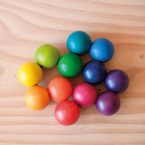 Der Kugelgreifling von Kokomoo flach aufgelegt am Boden, der leichte Glanz der Holzlasur und die unterschiedlichen 12 Regenbogenfarben sind gut zu erkennen.