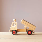 Der LKW-Kipper von Fagus aus Holz, seitlich zu sehen, wie er die Ladefläche abkippt.