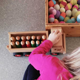 Blick von oben auf ein Kind, das gerade den LKW Muldenkipper von Fagus lenkt, die Ladefläche voll mit bunten Spielfiguren aus Holz.