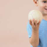 Ein lächelndes Kind hält den kleinen Lederball von Lautenbach, der einen Durchmesser von 9 cm hat, in der Hand.
