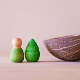 Eine kleine Kokosschale, daneben eine kleine grüne Holzfigur von Grapat und Mandala Legestein des Sets Bäume.