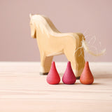 Drei Mandala Legesteine "Feuer" von Grapat in den drei verschiedenen Rottönen stehen vor einem Holzpferd von Ostheimer.