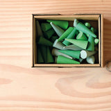 Die Mandala Steine Grapat "Green Cone" in Kegelform in verschiedenen Grüntönen liegen in ihrer Verpackung.
