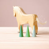 Eine Holzpferd Spielfigur, davor drei Mandala Steine von Grapat "Green Cone" - also drei kleine Kegel in verschiedenen Grüntönen.