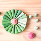 Grapat "Green Cone" - grüne Mandala Steine in Kegelform und ein rosa Mandalastein in Bütenform sind zu einer großen, runden Blüte aufgelegt.