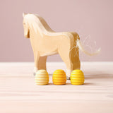 Holzpferd zum Spielen von Ostheimer, davor drei Mandala Steine Honigwaben von Grapat in den drei verschiedenen gelb Tönen.