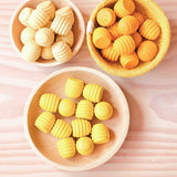 Drei mal zwölf Honigwaben Mandalasteine von Grapat in drei verschiedenen Gelbtönen, sortiert in Körben und Holzschalen.