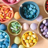 So viele verschiedene Mandala Legematerialien aus Holz in bunten Farben, sortiert nach Form und Farben in Körben, dazwischen liegen bunte Häkelbälle von Kokomoo.