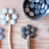 Aus Ästen, echten Steinen und dem Grapat Legematerial "Steine" sind Blumen auf dem Boden aufgelegt worden.