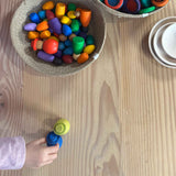 In einem Körbchen liegen verschiedene, bunte Spielfiguren aus Holz von Grapat, darunter auch die "Together" Menschenkinder Nins.