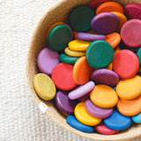 Ganz viele Coins Holzplättchen von Grapat in Regenbogenfarben liegen bunt gemischt in einem Körbchen.