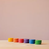 Coins von Grapat in Regenbogenfarben: die bunten 18 Holzplättchen sind nach Farben sortiert, je ein Stapel mit 3 Plättchen nebeneinander.
