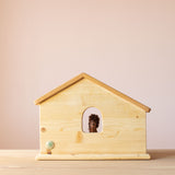 Drei Blätter Pferdestall zum Spielen aus Holz von der Rückseite. Ein kleines Spielzeug Pferd aus Filz schaut beim Fenster heraus.