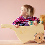 Ein kleines Kind sitzt samt ihrer Puppe in der Schubkarre aus Holz von Lautenbach.