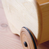 Eine Detailaufnahme der Schubkarre aus Holz von Lautenbach, bei der das Holzrad mit der Gummibereifung und die Holzmaserung gut zu sehen sind.