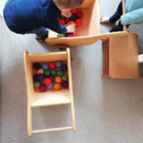 Zwei Kinder verladen bunte Filzbälle von Kokomoo in zwei Schubkarren aus Holz von Lautenbach.