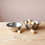 Zwei Schüsseln aus Edelstahl, eine leer, eine gefüllt mit Korken. Zwei Korken liegen noch vor den Edelstahl-Schüsseln.