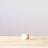 Ein Serviettenring aus Holz, konkave, nach innen gewölbte Form von der Seite betrachtet.