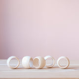 Fünf Serviettenringe aus Holz von Kokomoo in klassischer Form konkav nach innen gebogen stehen auf Ihrer Kante.