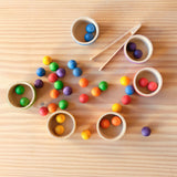 Grapat "Bowls and Marbles" Sortierspiel von oben mit den sechs Schälchen in Regenbogenfarben, den 36 kleinen Holzkugeln und der kleinen Holzzange.