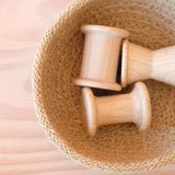 Drei Stück Grapat "Spools" Spulen aus Holz in drei verschiedenen Formen liege in einem Jutekörbchen.