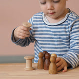 Ein Kind spielt mit den Grapat Nins Holzfiguren und mit den"Spools" Spulen aus Holz.